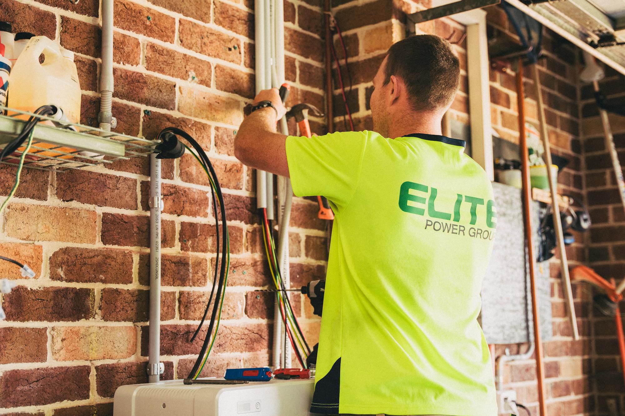 Electrician in safety gear working on a residential solar battery storage installation