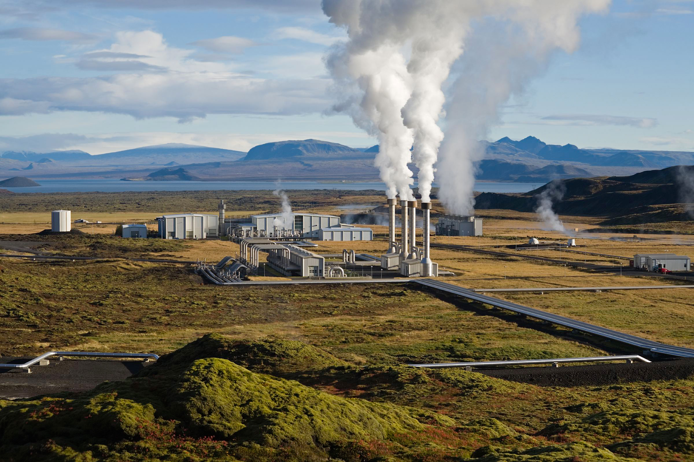 Nesjavellir geothermal power plant in Iceland with steam columns rising from the facility against a mountainous backdrop