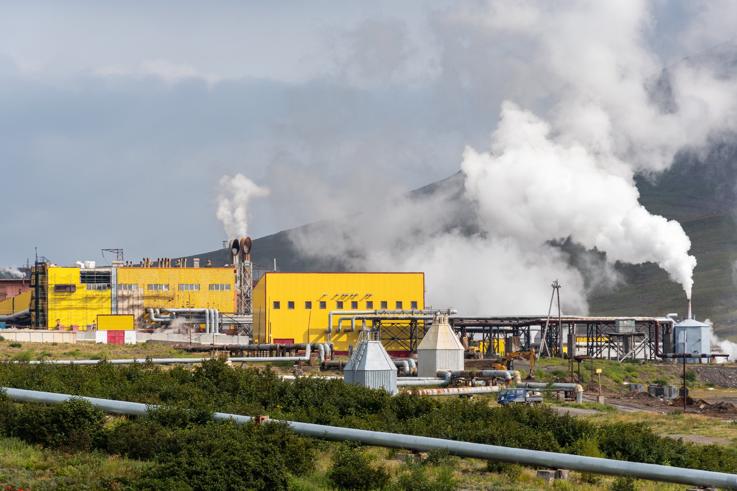 Mutnovsky geothermal power plant in Kamchatka, Russia, with steam rising against a volcanic mountain backdrop