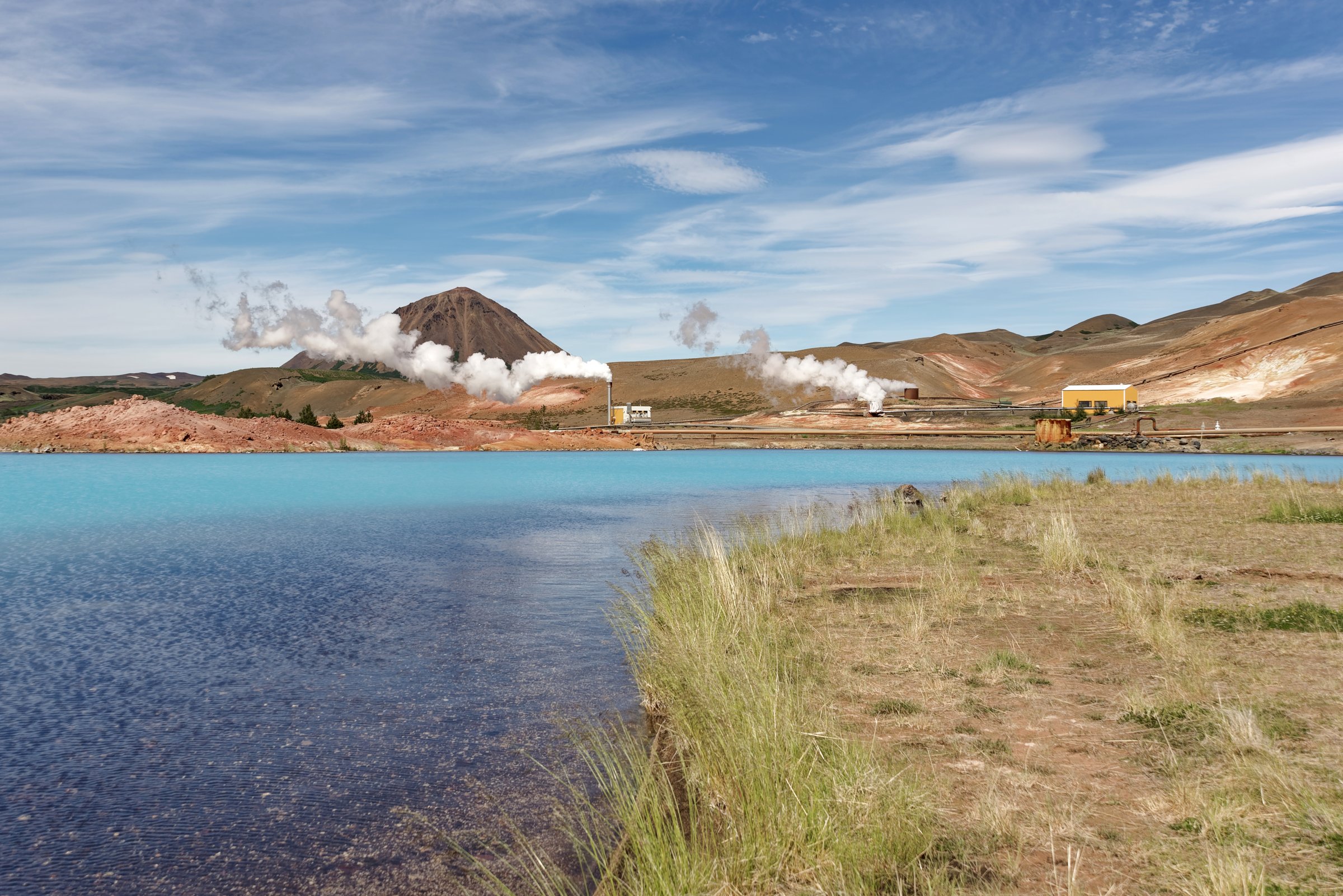 Bjarnarflag geothermal power station in Iceland with the turquoise Blue Lake and steam rising from the volcanic landscape
