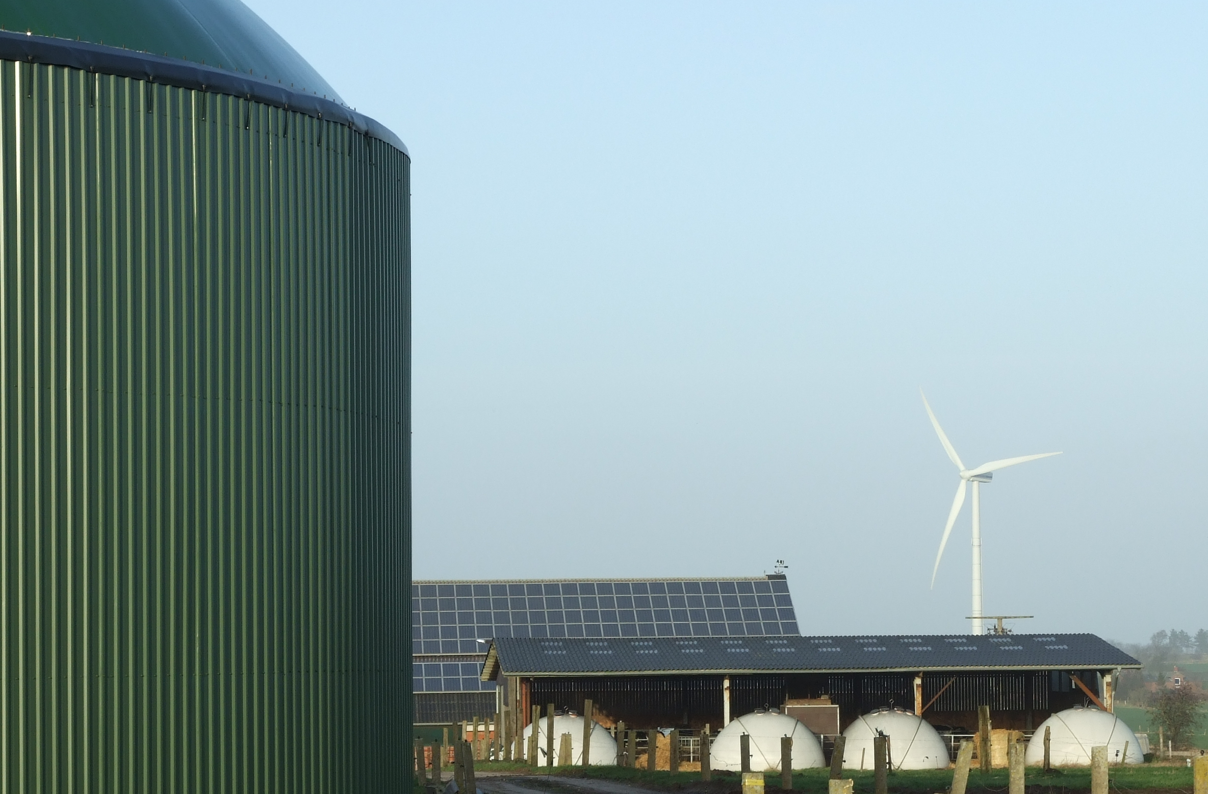 Biogas fermenter alongside a wind turbine and solar panels on a farm in Horstedt, Schleswig-Holstein, Germany