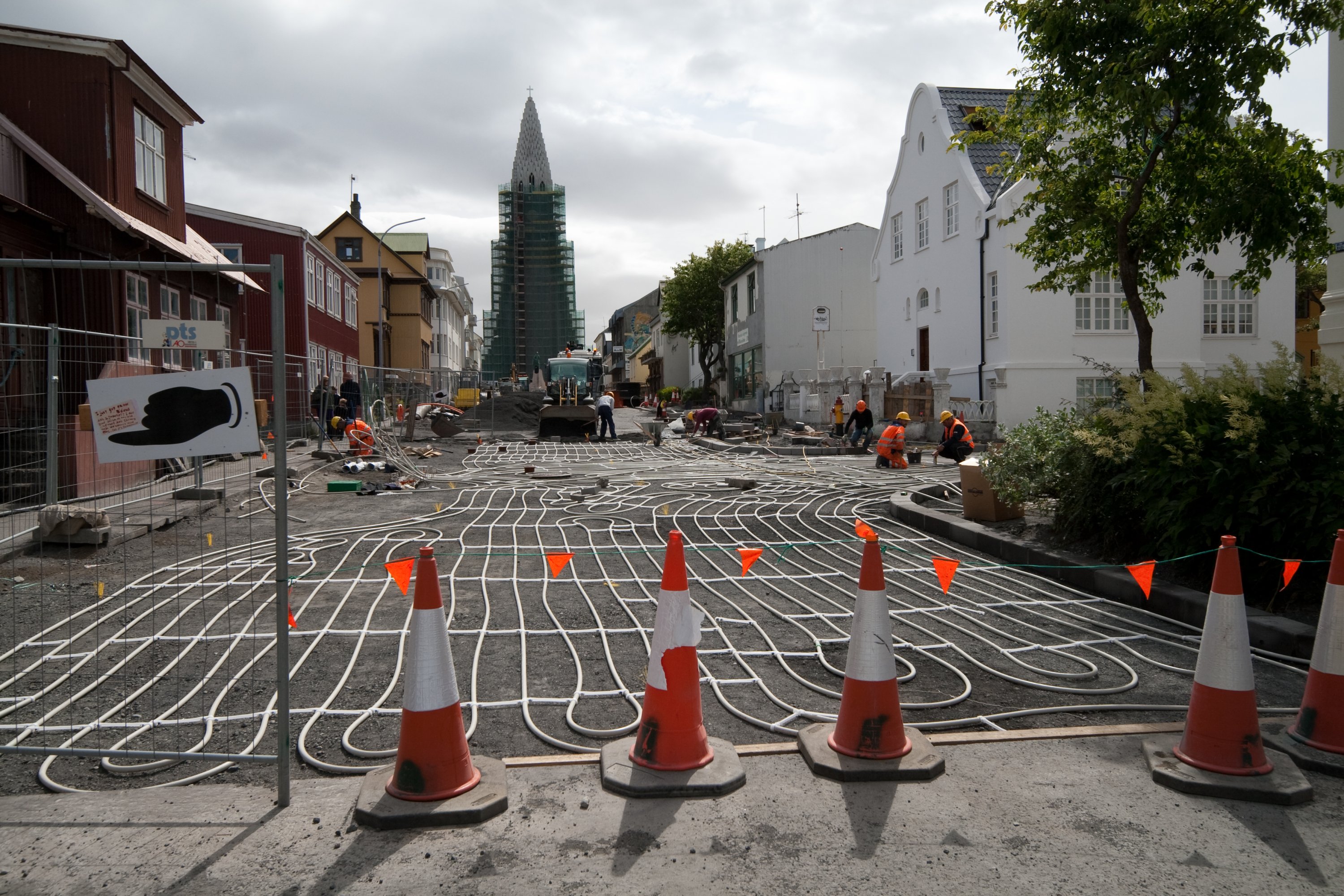 Geothermal hot water pipes exposed beneath a street surface in Iceland, showing the district heating infrastructure that delivers heat to buildings