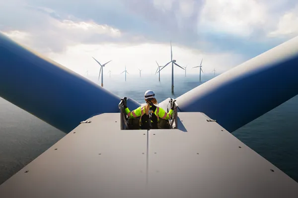 A technician standing atop the nacelle of a wind turbine